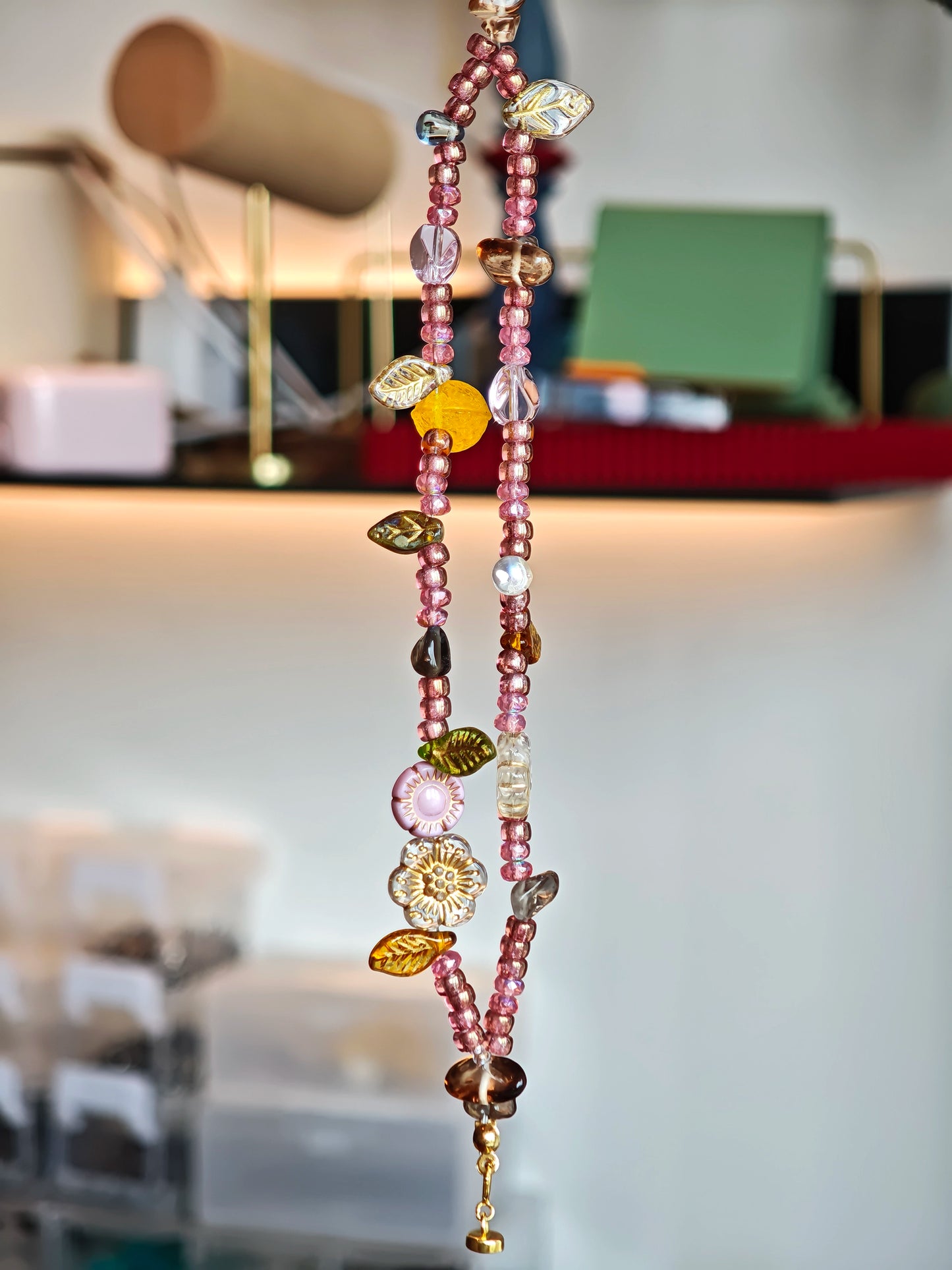 This is a pink czech beads bracelet, decorated with green leaves , yellow lemon, flowers and irregularly shape amber color beads.