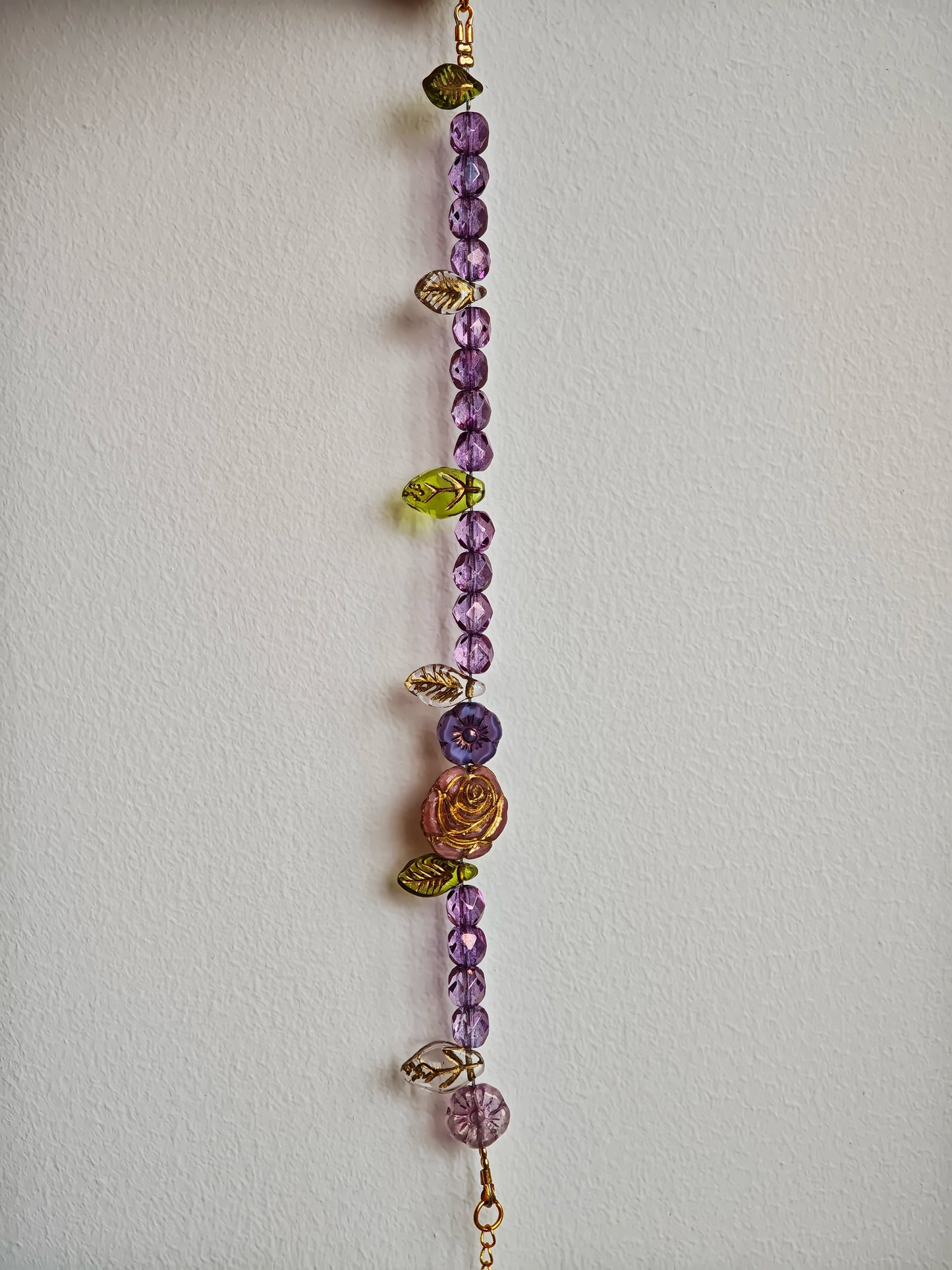 A purple hand-strung bracelet with luminous Czech glass beads & delicate botanical charms.