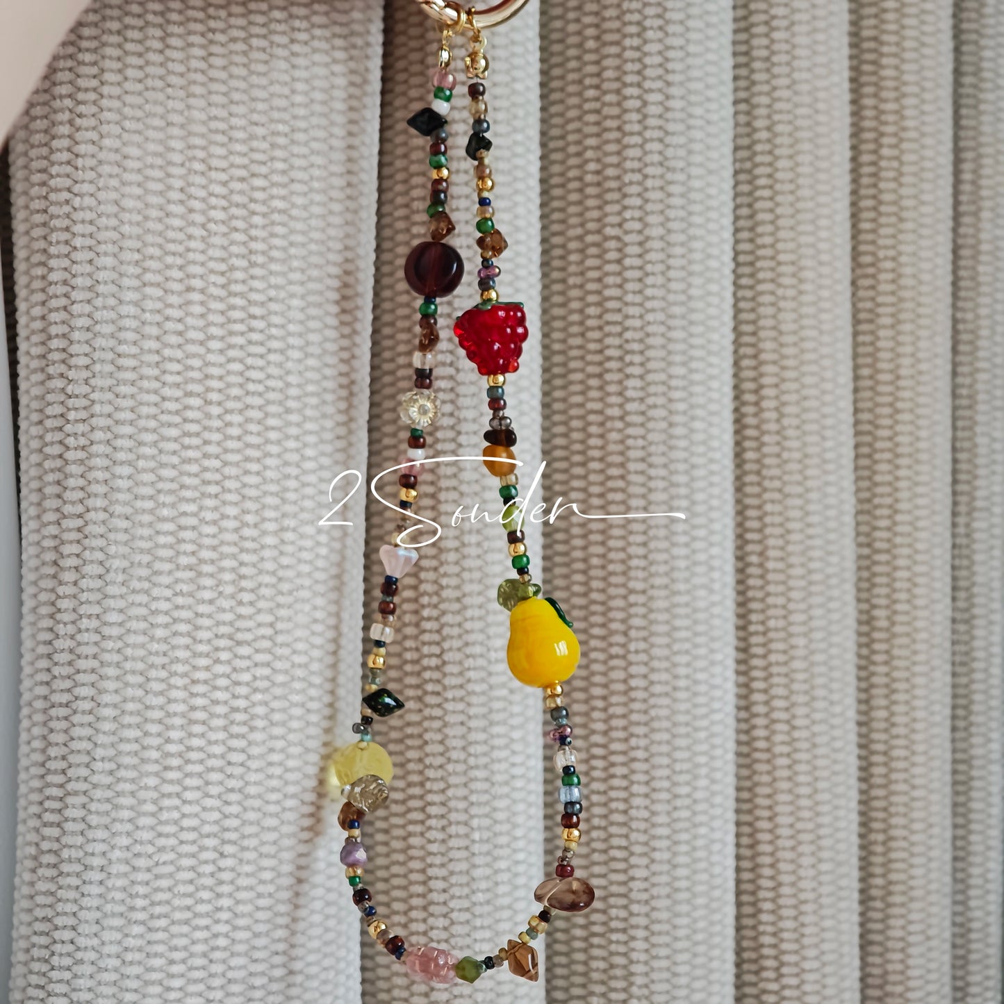 This handmade Czech glass bead bag charm is also perfect as a phone strap, keychain accessory, or a car decor. Featuring translucent beads, fruity spacers (pear, lemon, strawberry!), whimsical floral leaves and durable gold-tone hardware, it’s like wearing a garden on your keys.