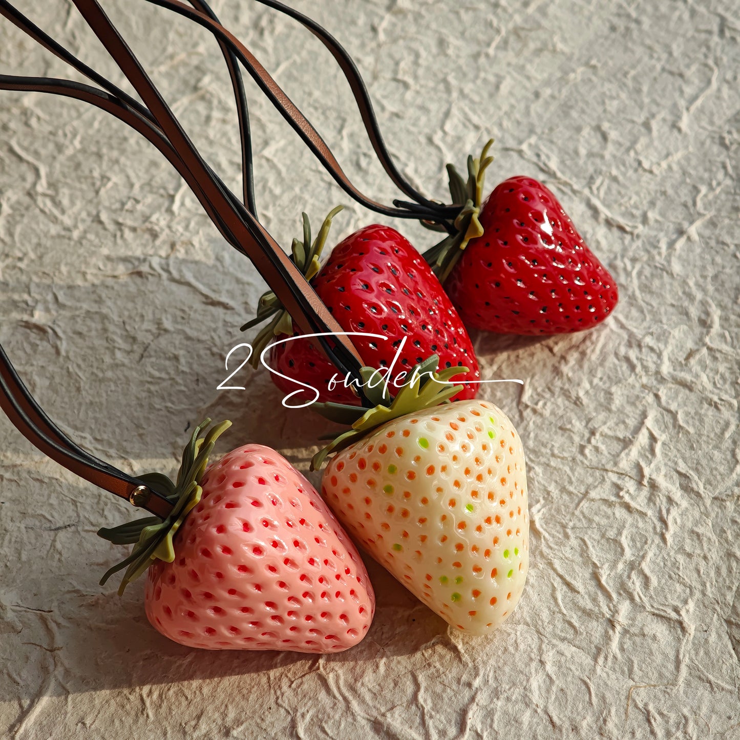 This is a simulated strawberry bag charm. The charm features a strawberry, the same size as a real strawberry, and is made of high-quality resin, giving it a very realistic appearance. It also has a leather cord attached, allowing it to be hung on bags, earphone cases, or used as a keychain. It's versatile and very cute.