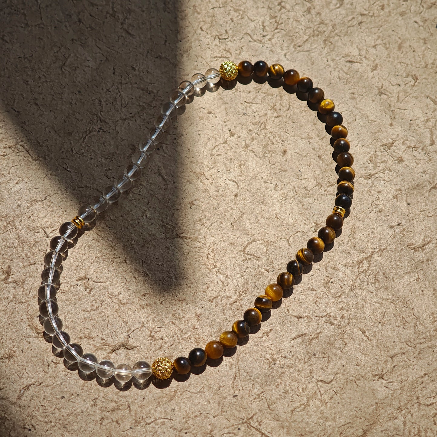 This is a necklace with tiger's eye, clear quartz, gold-plated spacer and elastic cord.