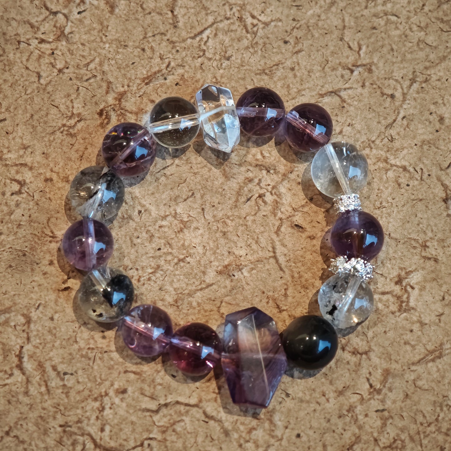 An amethyst bracelet accented with herkimer diamond, clear quartz and silver sheen obsidian.