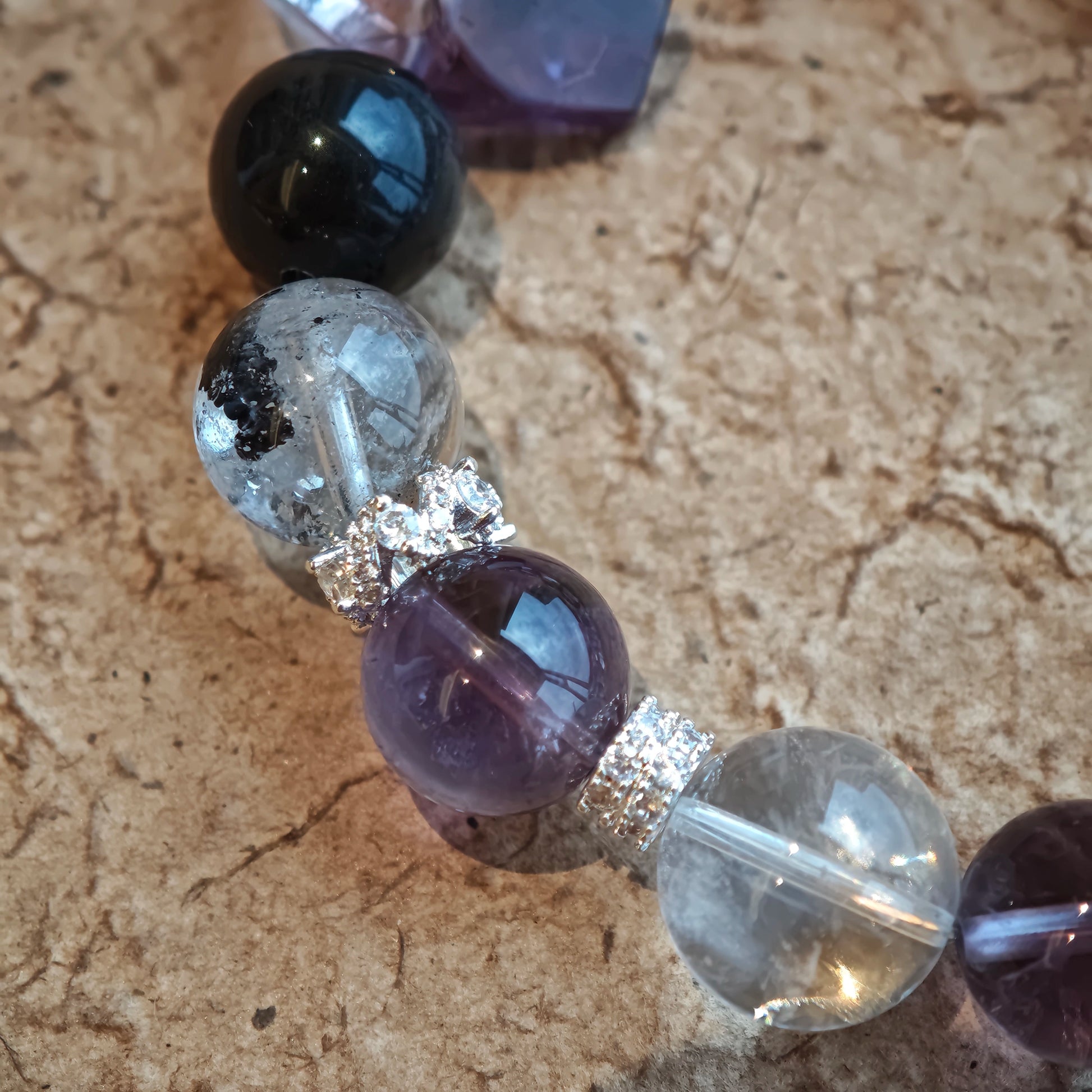 An amethyst bracelet accented with herkimer diamond, clear quartz and silver sheen obsidian.