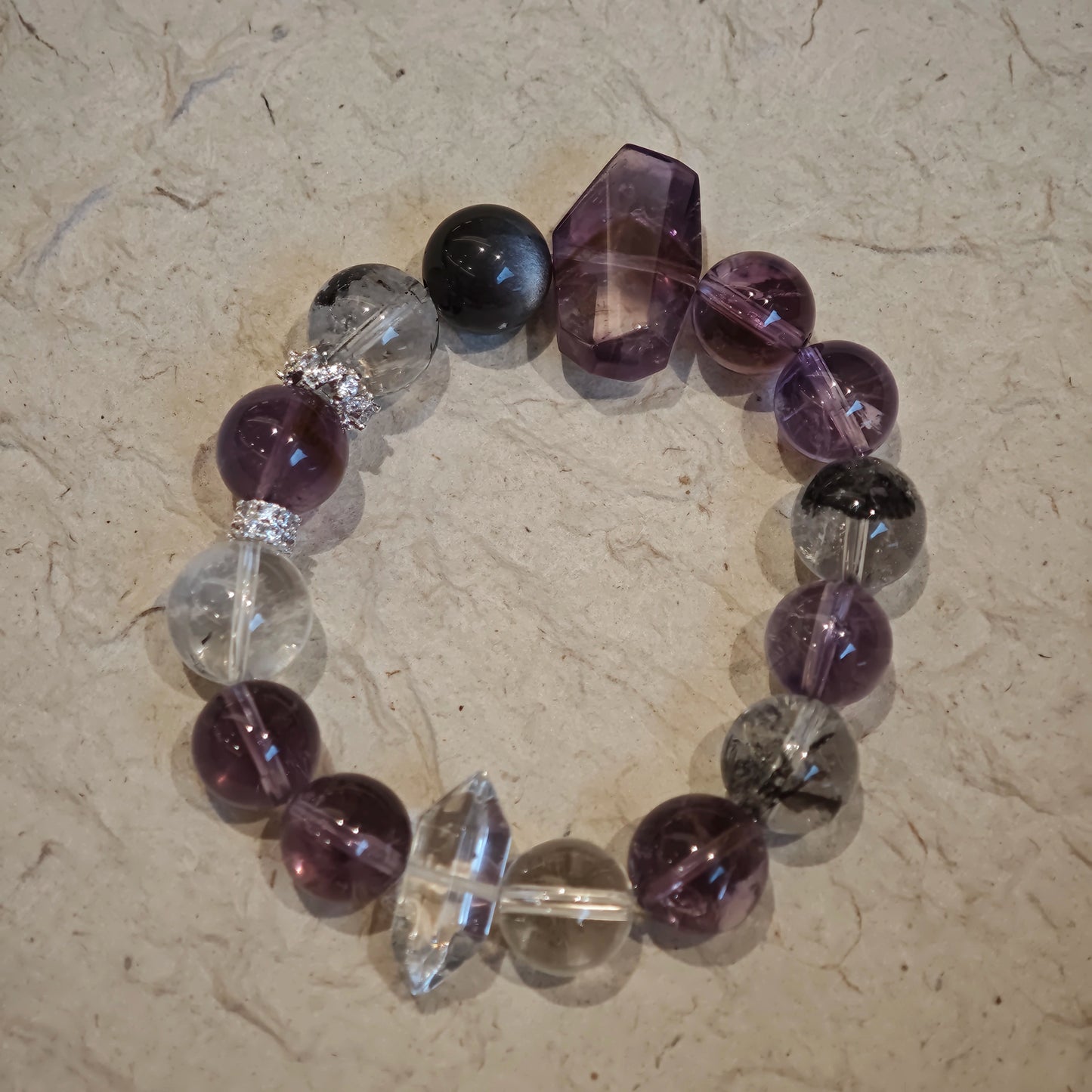 An amethyst bracelet accented with herkimer diamond, clear quartz and silver sheen obsidian.