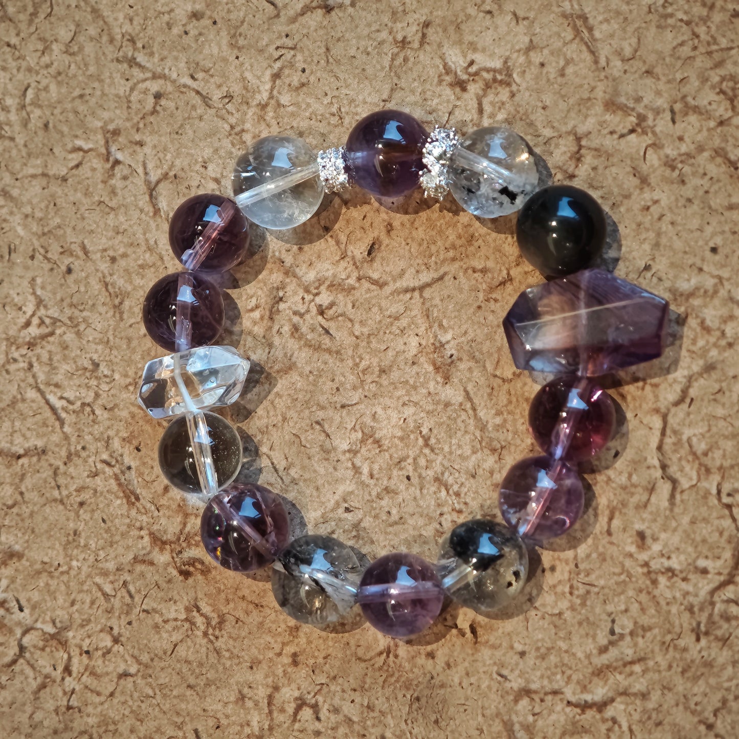 An amethyst bracelet accented with herkimer diamond, clear quartz and silver sheen obsidian.