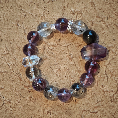 An amethyst bracelet accented with herkimer diamond, clear quartz and silver sheen obsidian.