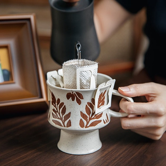 This is a 300ml ceramic goblet mug with hand-painted leaf or flower patterns and a matte sesame-speckled glaze design. With mouth diameter of 9.7, bottom diameter of 6.7cm and height of 10.5cm, this mug is ideal for coffee, milk, water, or oatmeal during slow mornings or quiet afternoons.