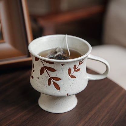 This is a 300ml ceramic goblet mug with hand-painted leaf or flower patterns and a matte sesame-speckled glaze design. With mouth diameter of 9.7, bottom diameter of 6.7cm and height of 10.5cm, this mug is ideal for coffee, milk, water, or oatmeal during slow mornings or quiet afternoons.