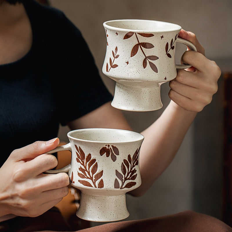 This is a 300ml ceramic goblet mug with hand-painted leaf or flower patterns and a matte sesame-speckled glaze design. With mouth diameter of 9.7, bottom diameter of 6.7cm and height of 10.5cm, this mug is ideal for coffee, milk, water, or oatmeal during slow mornings or quiet afternoons.