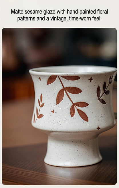 This is a 300ml ceramic goblet mug with hand-painted leaf or flower patterns and a matte sesame-speckled glaze design. With mouth diameter of 9.7, bottom diameter of 6.7cm and height of 10.5cm, this mug is ideal for coffee, milk, water, or oatmeal during slow mornings or quiet afternoons.