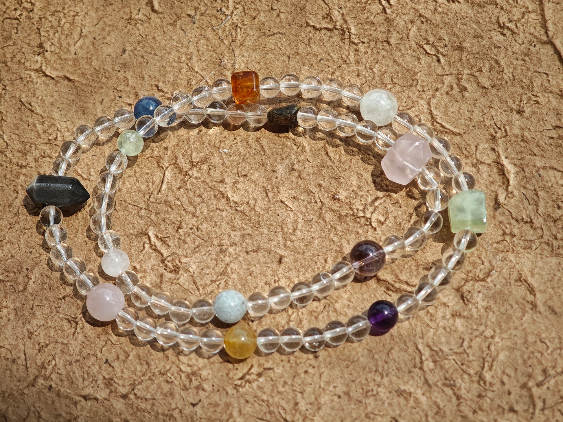 A multi-gemstone bracelet which is made with Silver Sheen Obsidian, Clear Quartz, Amethyst, Rose Quartz, Kyanite, Citrine, and Prehnite, etc. It’s also a necklace.