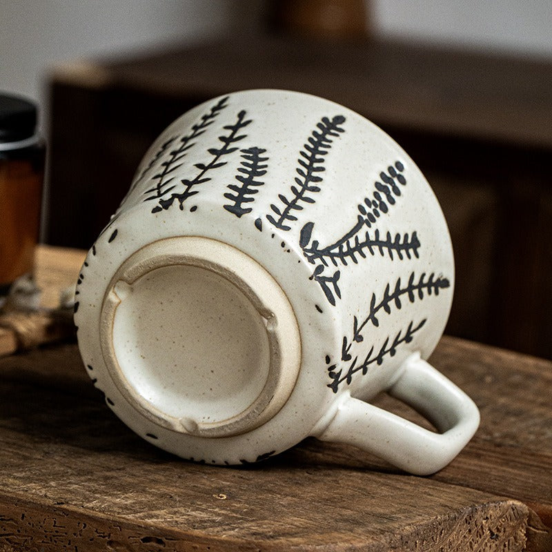 This is a 325ml coarse ceramic mug with a matte sesame-speckled glaze and hand-painted leaf design. It comes with a rounded handle that sits comfortably in your hand. Ideal for coffee, milk, water, or oatmeal during slow mornings or quiet afternoons.