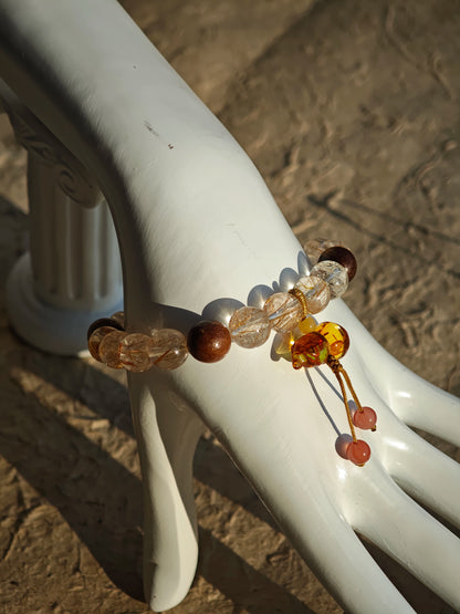 Copper galaxies glitter inside each bead, agarwood whispers mantras, and the floral calabash locks luck in its curl.