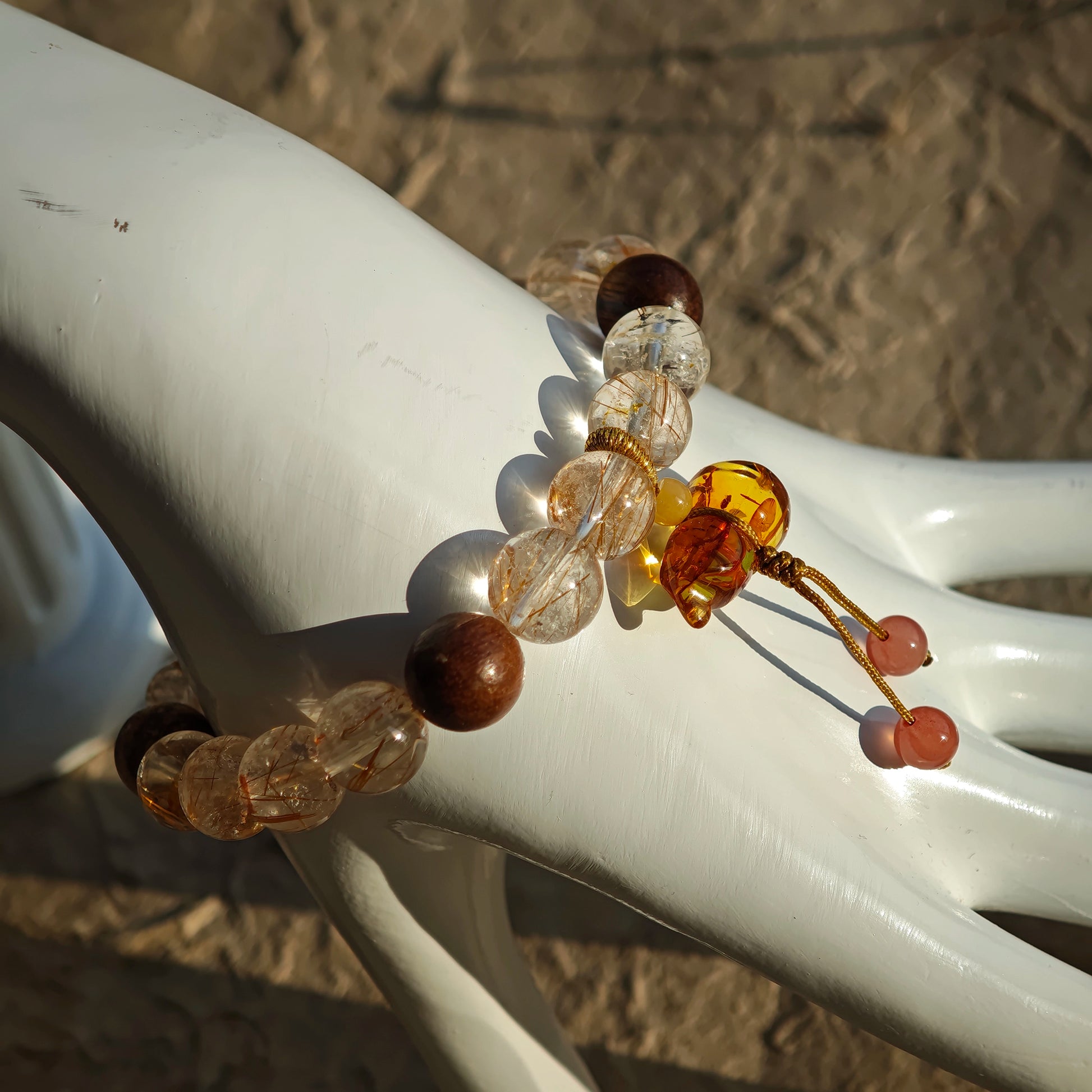 This crystal bracelet weaves Copper Rutilated Quartz together with aromatic Agarwood beads, then finishes with a Nanhong-carved flower-amber calabash that whispers prosperity and protection.