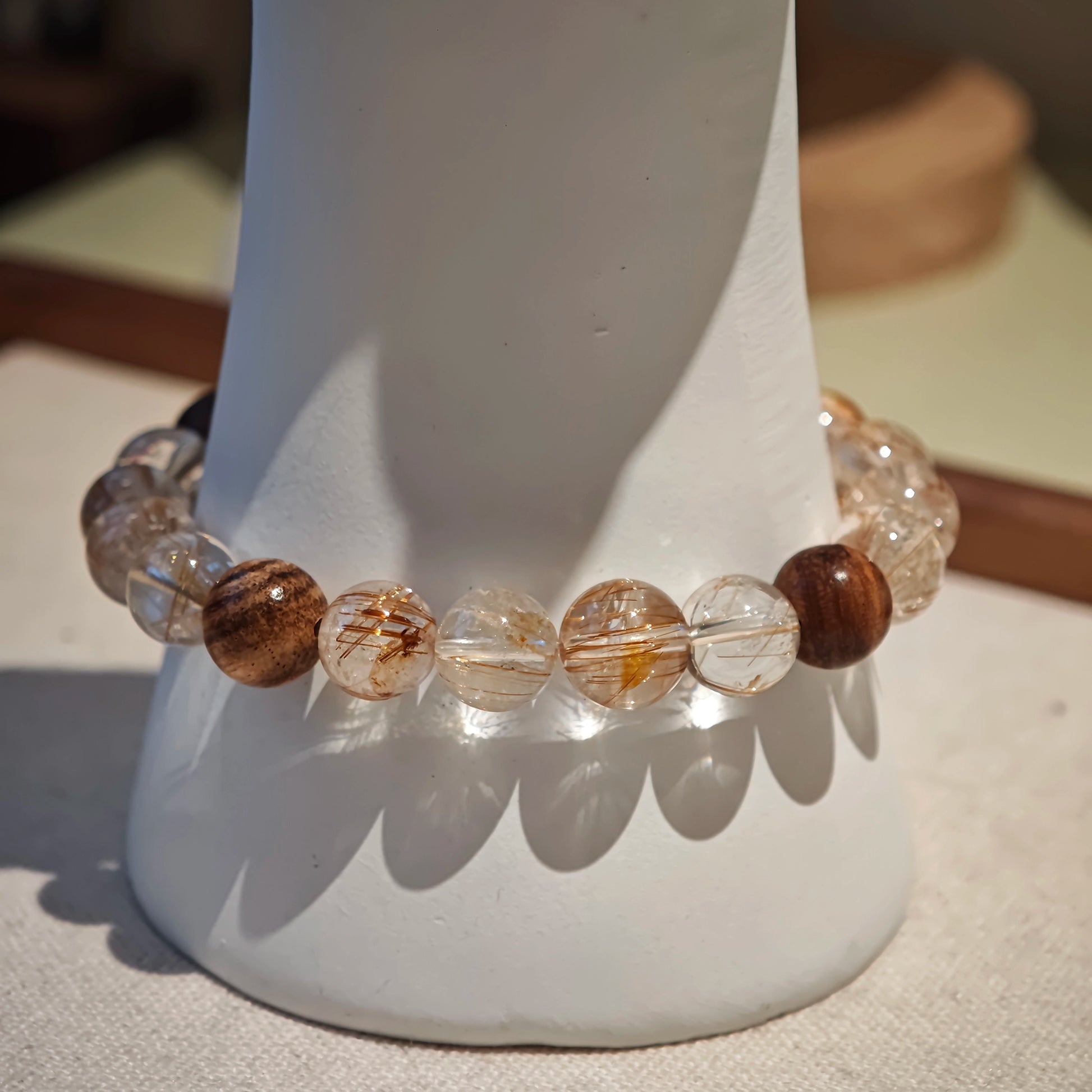 The strand tells a story: copper energy rises, agarwood grounds, and the amber gourd keeps both treasure and talisman.