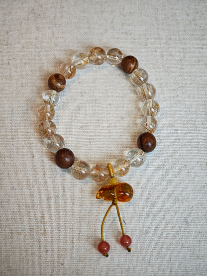 This crystal bracelet unites copper-rutilated quartz with aromatic agarwood beads, finished by a Nanhong-carved flower-amber gourd that symbolizes prosperity and protection.