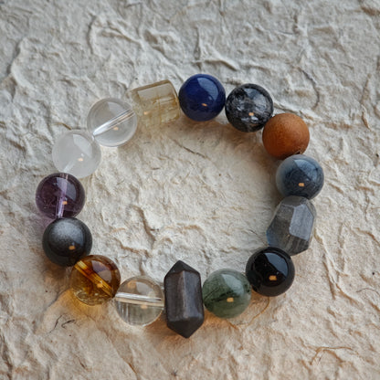 A monochrome rainbow—silver rutile, white phantom, pale citrine, violet amethyst, blue moonstone, gunmetal obsidian.