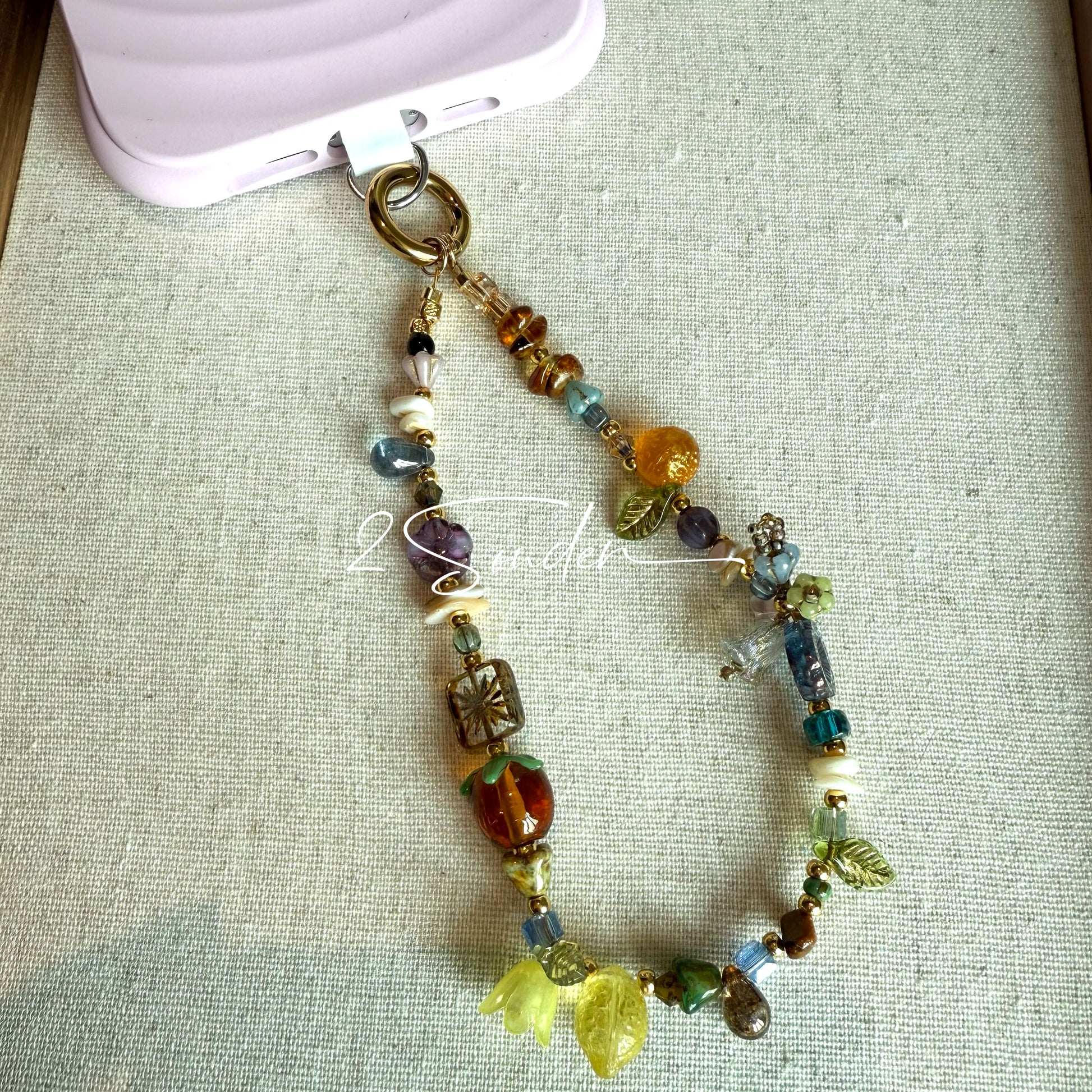 This is a bag charm that made of Czech beads. In the phone strap, there are different spacers like orange, leaves, flowers and lemon. It's with multi colors. This bag charm can also be used as a phone strap and key chain.