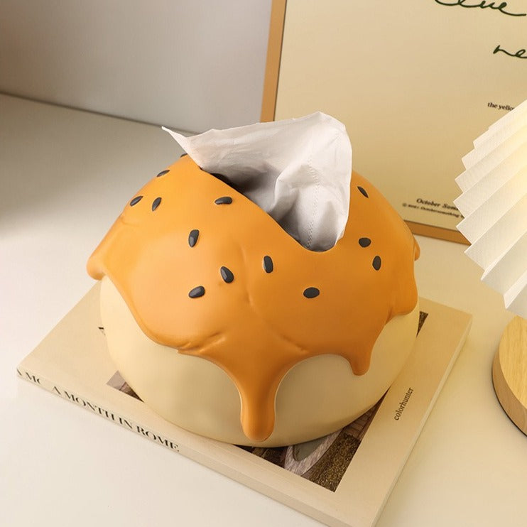 This is tissue box cover with an egg yolk pastry shape. On the lifelike flaky pstry surface, there are sesame seeds and a wide enough opening for pulling out tissues.