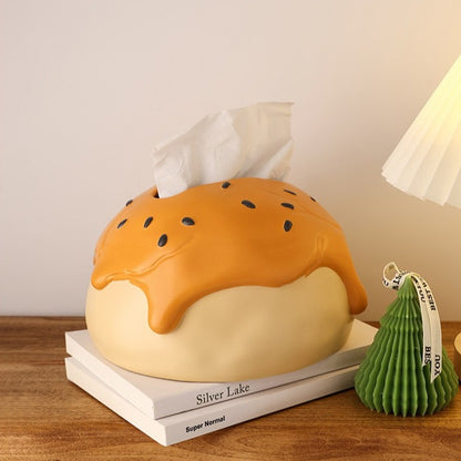 This is tissue box cover with an egg yolk pastry shape. On the lifelike flaky pstry surface, there are sesame seeds and a wide enough opening for pulling out tissues.