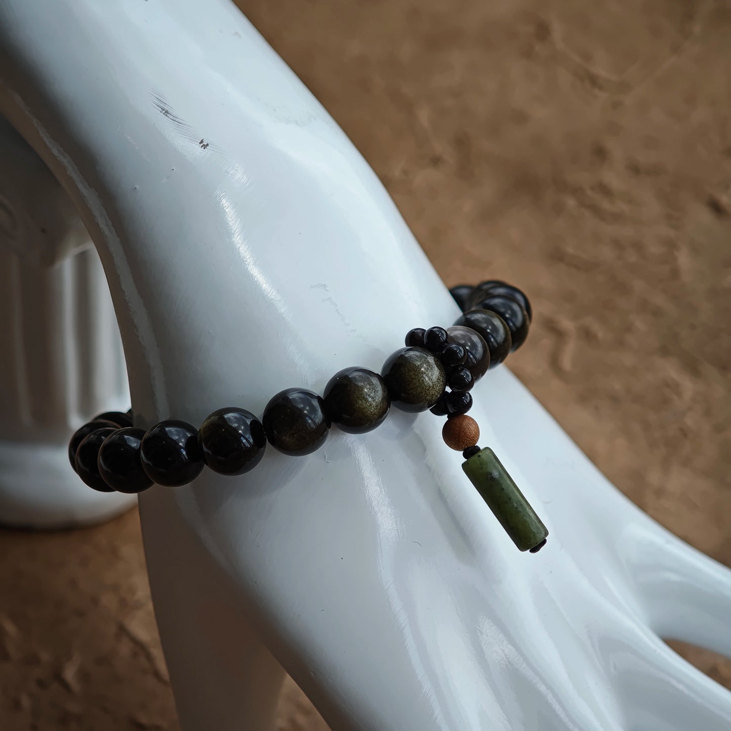 A minimalist strand of 8 mm obsidian beads gains Chinese soul through rutile glint and a sandalwood-agate drop.