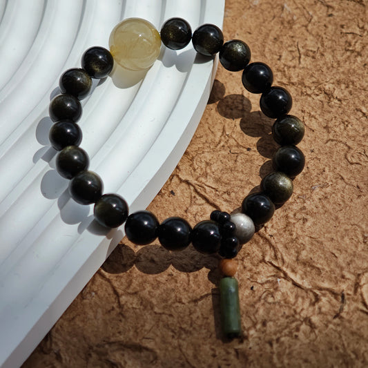 Clean lines of gold- and silver-sheen obsidian cradle a rutile bead and a sandalwood-black agate charm.