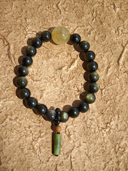Radiant gold- and silver-obsidian orbs, a single rutile bead, and a sandalwood-agate pendant meld into a protective, culturally rich bracelet.
