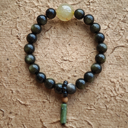 Eight-millimeter obsidian guardians circle the wrist, accented by rutilated quartz and a carved sandalwood-black agate token of China’s charm.