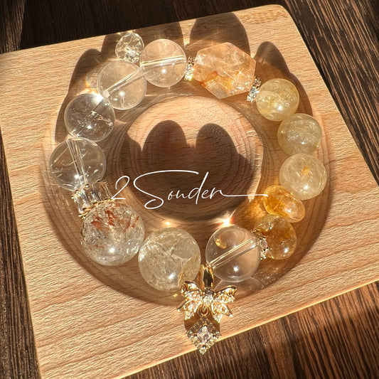 This is a gemstone bracelet made of Golden Hematoid Quartz, Copper Rutilated Quartz, Clear Quartz and Citrine. In the bracelet, there is also a bow pendant as decoration.