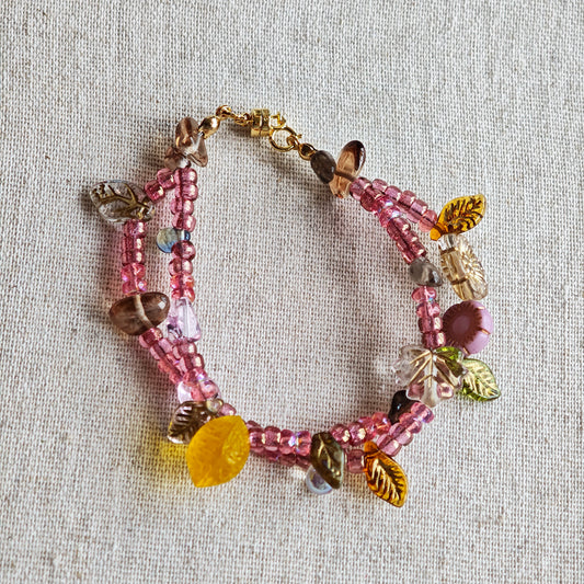 This is a pink czech beads bracelet, decorated with green leaves , yellow lemon, flowers and irregularly shape amber color beads.