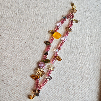 This is a pink czech beads bracelet, decorated with green leaves , yellow lemon, flowers and irregularly shape amber color beads.