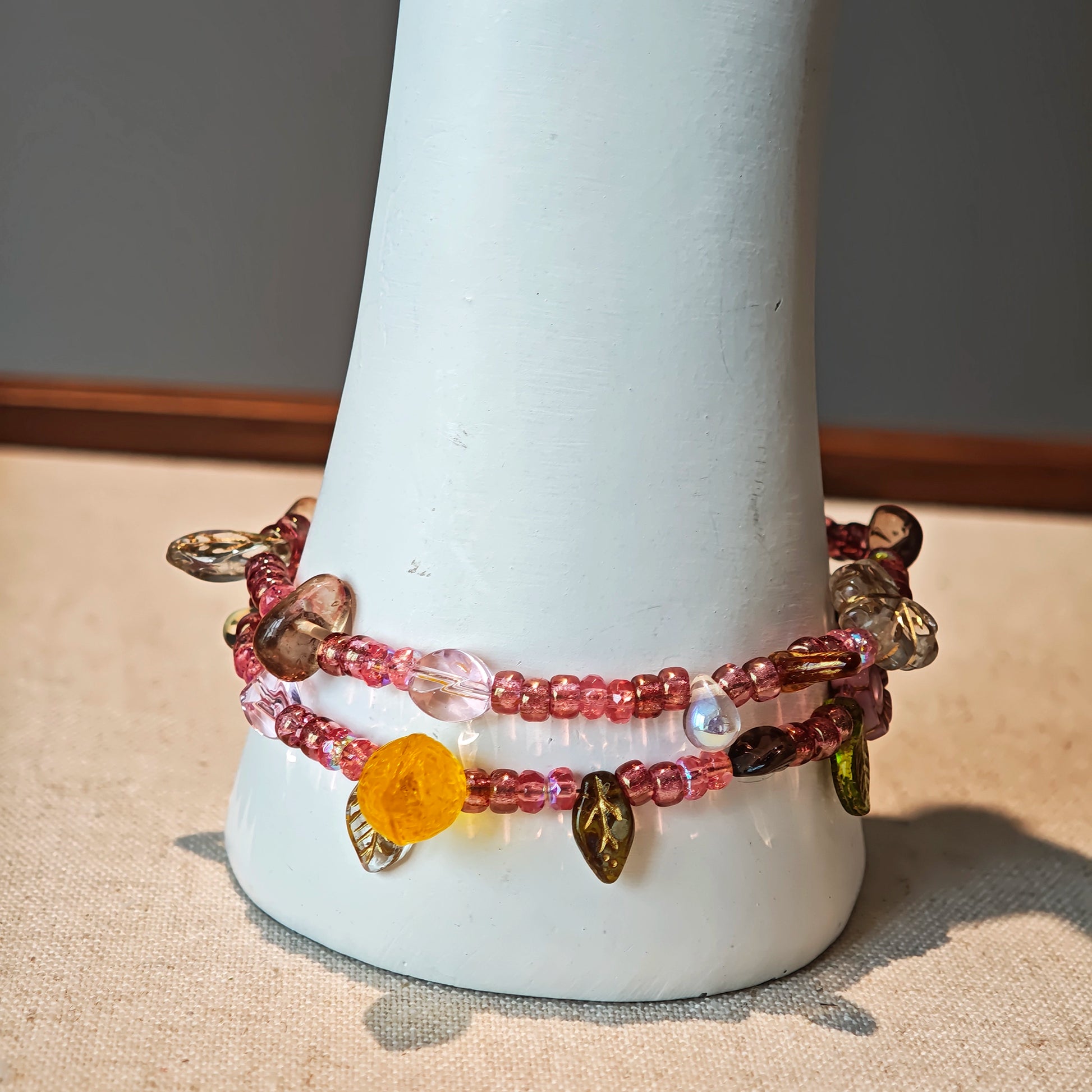 This is a pink czech beads bracelet, decorated with green leaves , yellow lemon, flowers and irregularly shape amber color beads.