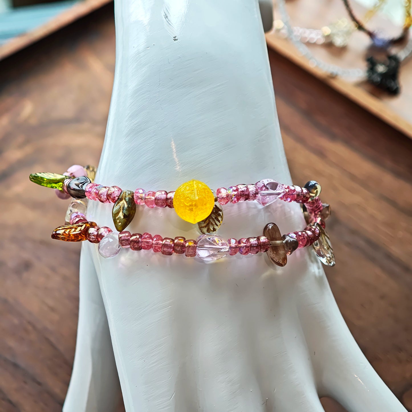 This is a pink czech beads bracelet, decorated with green leaves , yellow lemon, flowers and irregularly shape amber color beads.