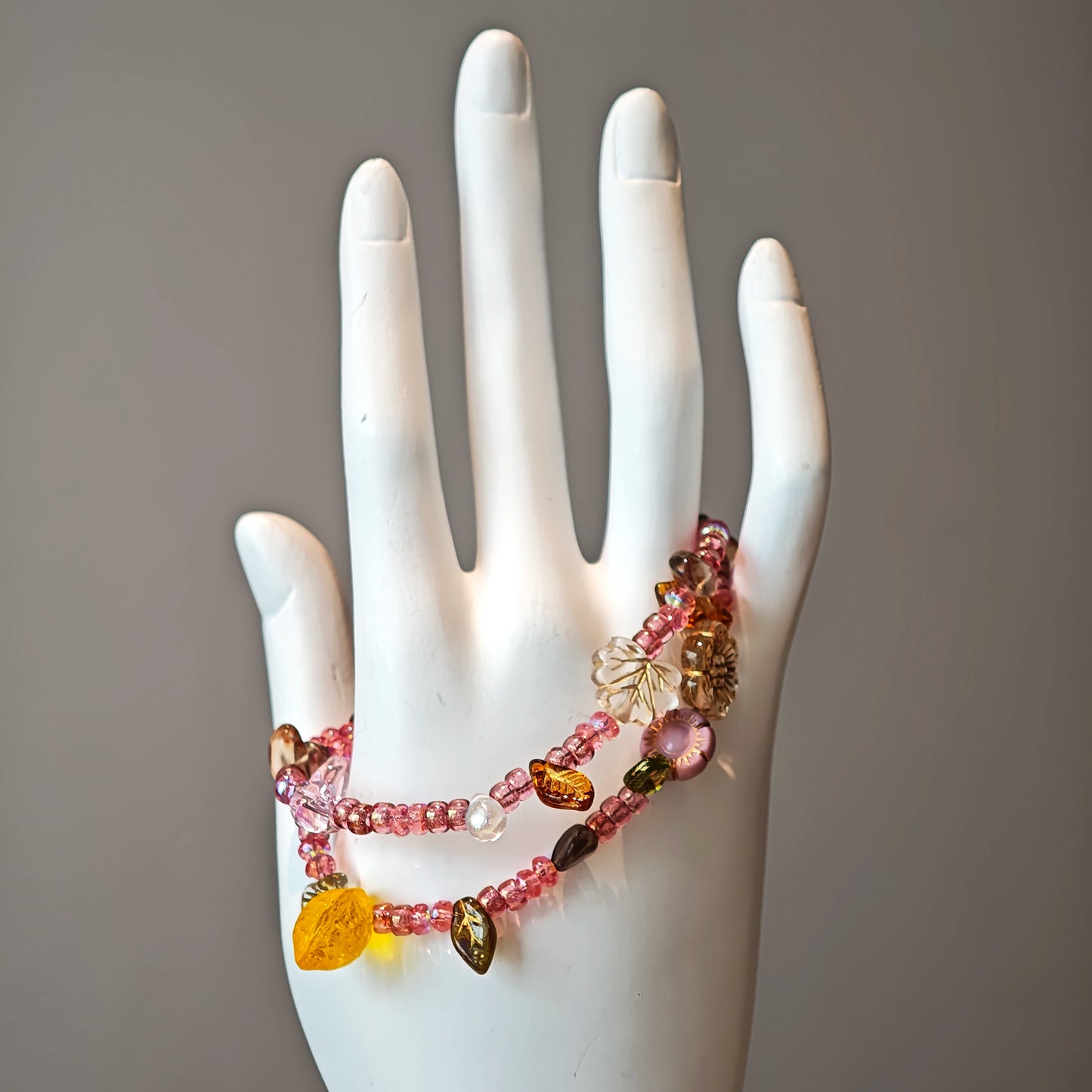 This is a pink czech beads bracelet, decorated with green leaves , yellow lemon, flowers and irregularly shape amber color beads.
