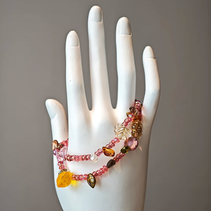 This is a pink czech beads bracelet, decorated with green leaves , yellow lemon, flowers and irregularly shape amber color beads.