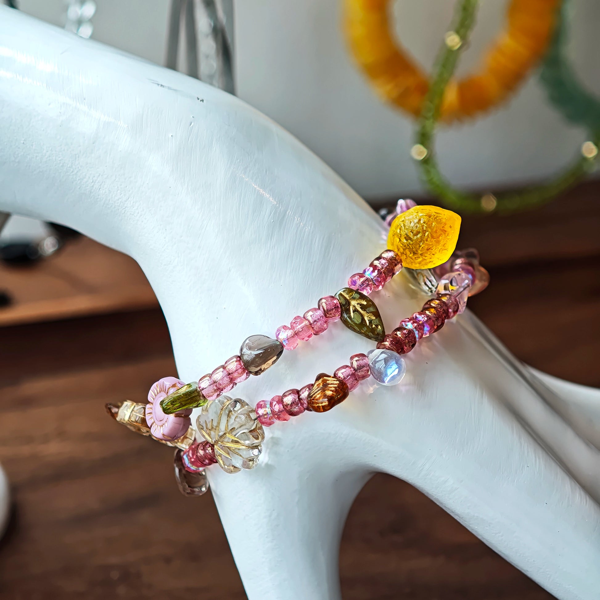 This is a pink czech beads bracelet, decorated with green leaves , yellow lemon, flowers and irregularly shape amber color beads.