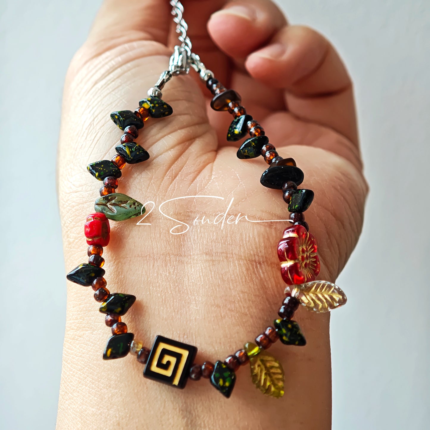 This is a bracelet crafted with rich terracotta glass beads that glow like aged parchment. It captures the warmth of a late autumn sunset. In the bracelet, there are various leaves, flowers, and irregularly shaped spacers. It’s the perfect piece of vintage jewelry to add a touch of nostalgia to your daily rotation.