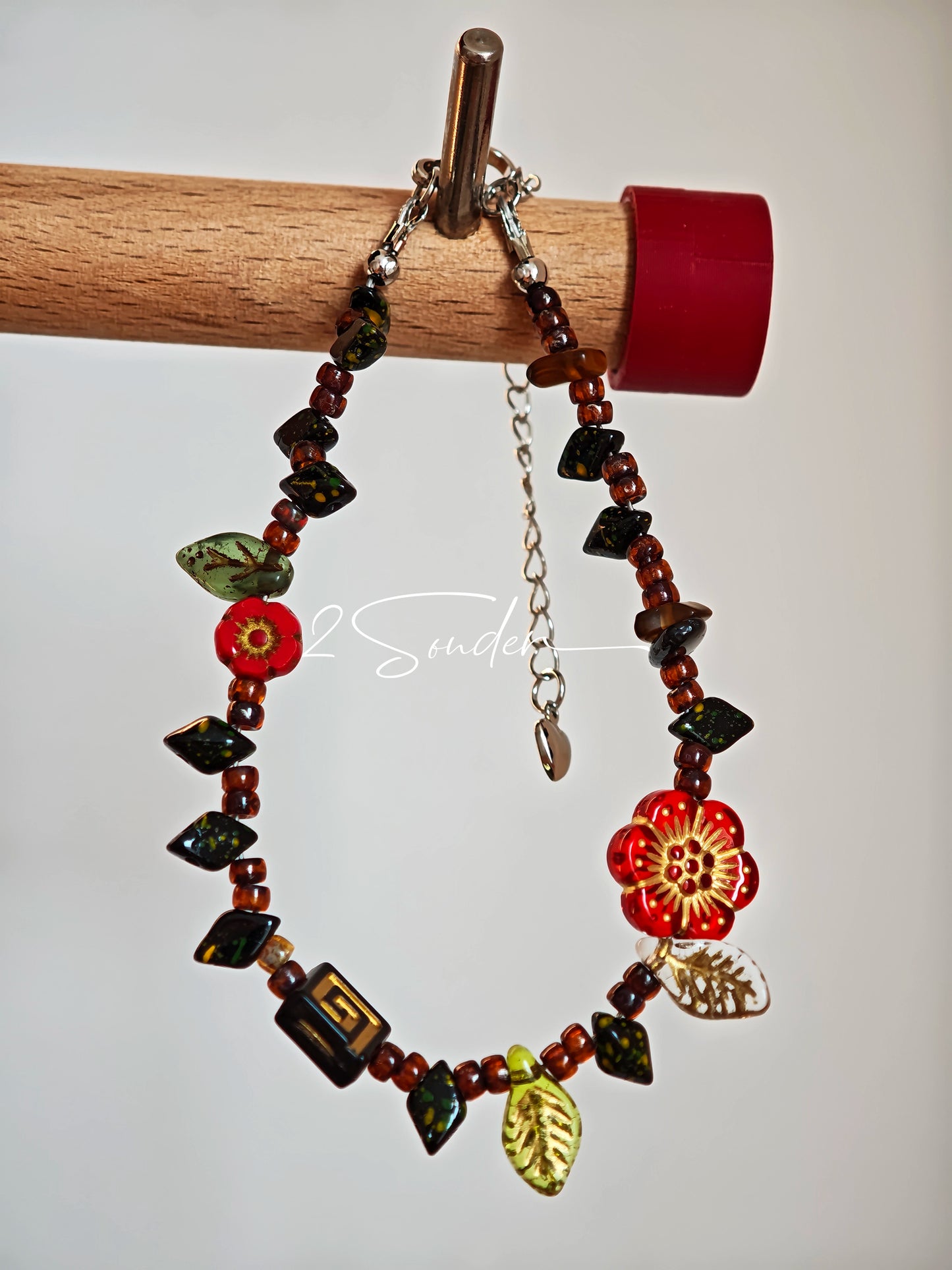 This is a bracelet crafted with rich terracotta glass beads that glow like aged parchment. It captures the warmth of a late autumn sunset. In the bracelet, there are various leaves, flowers, and irregularly shaped spacers. It’s the perfect piece of vintage jewelry to add a touch of nostalgia to your daily rotation.