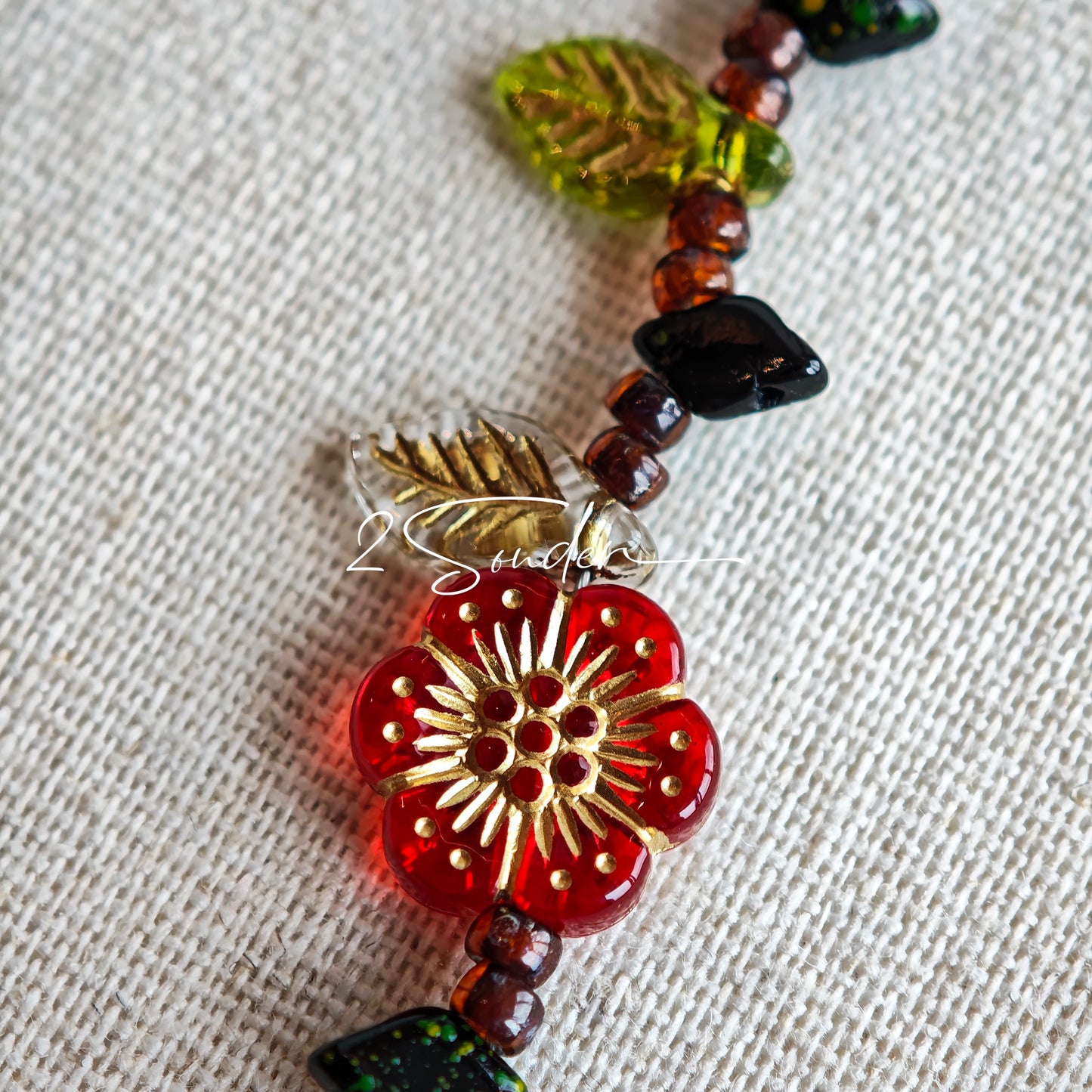 This is a bracelet crafted with rich terracotta glass beads that glow like aged parchment. It captures the warmth of a late autumn sunset. In the bracelet, there are various leaves, flowers, and irregularly shaped spacers. It’s the perfect piece of vintage jewelry to add a touch of nostalgia to your daily rotation.