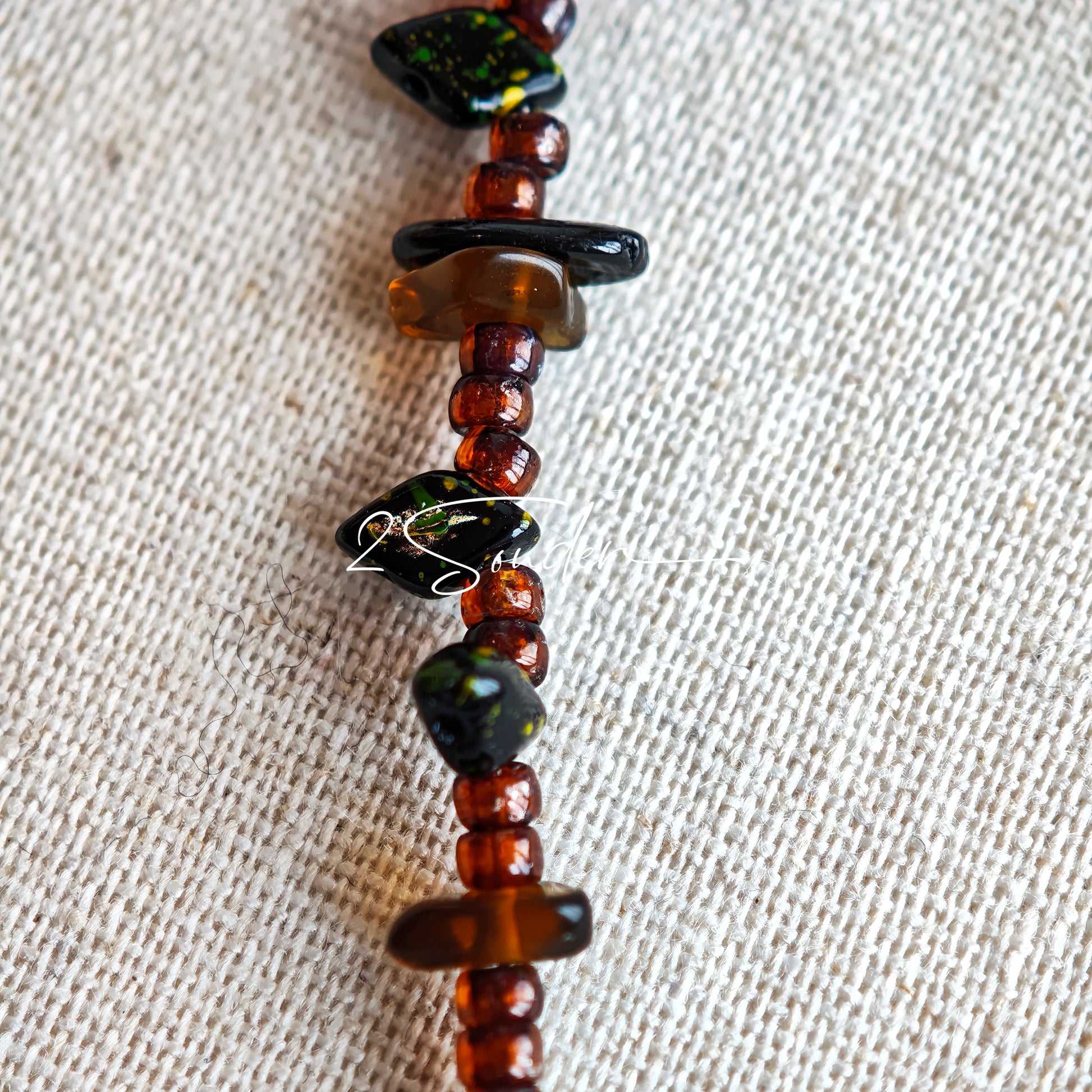 This is a bracelet crafted with rich terracotta glass beads that glow like aged parchment. It captures the warmth of a late autumn sunset. In the bracelet, there are various leaves, flowers, and irregularly shaped spacers. It’s the perfect piece of vintage jewelry to add a touch of nostalgia to your daily rotation.