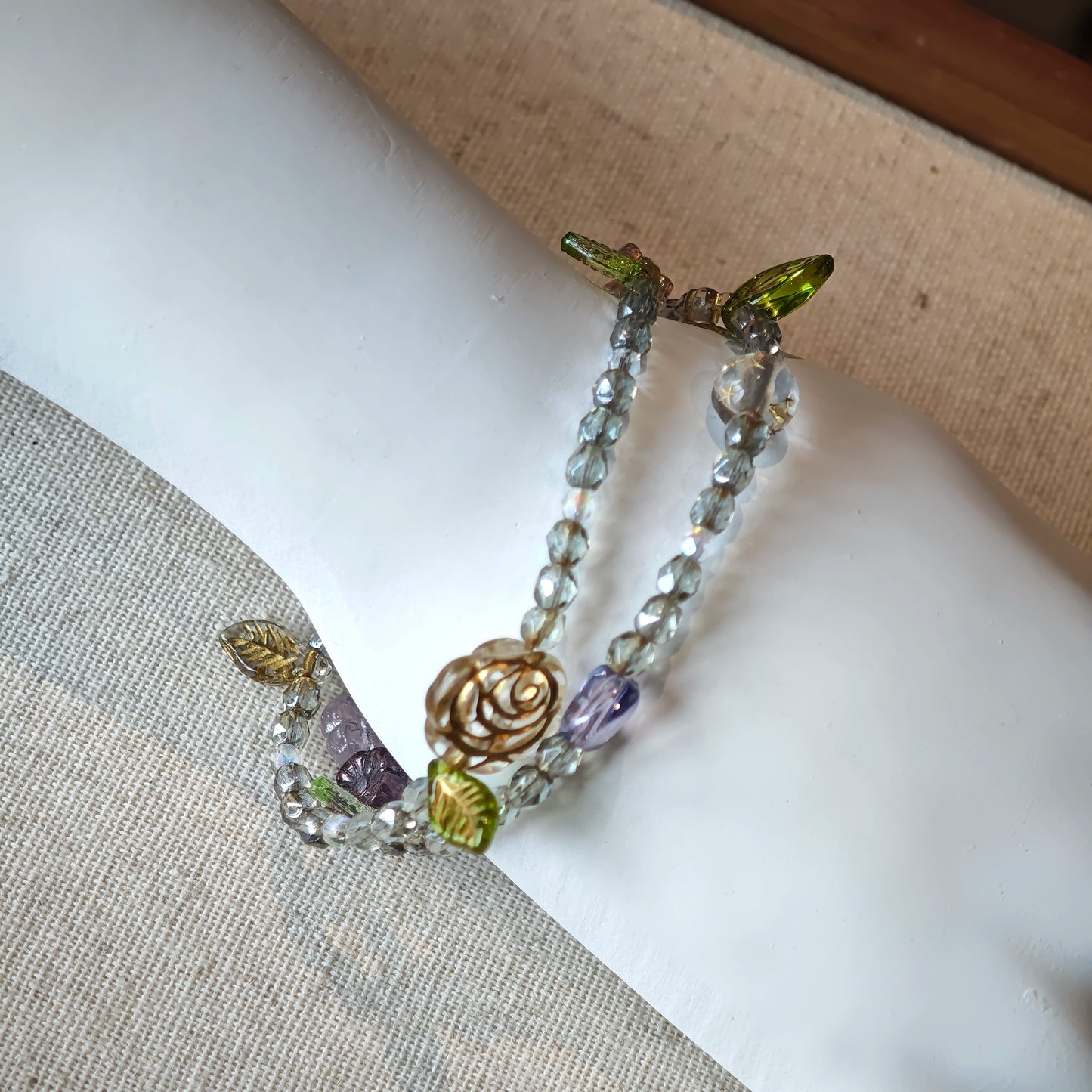 This is a grey czech beads bracelet, decorated with green leaves , bronze and purple flowers, and irregularly shape amber color spacer beads.