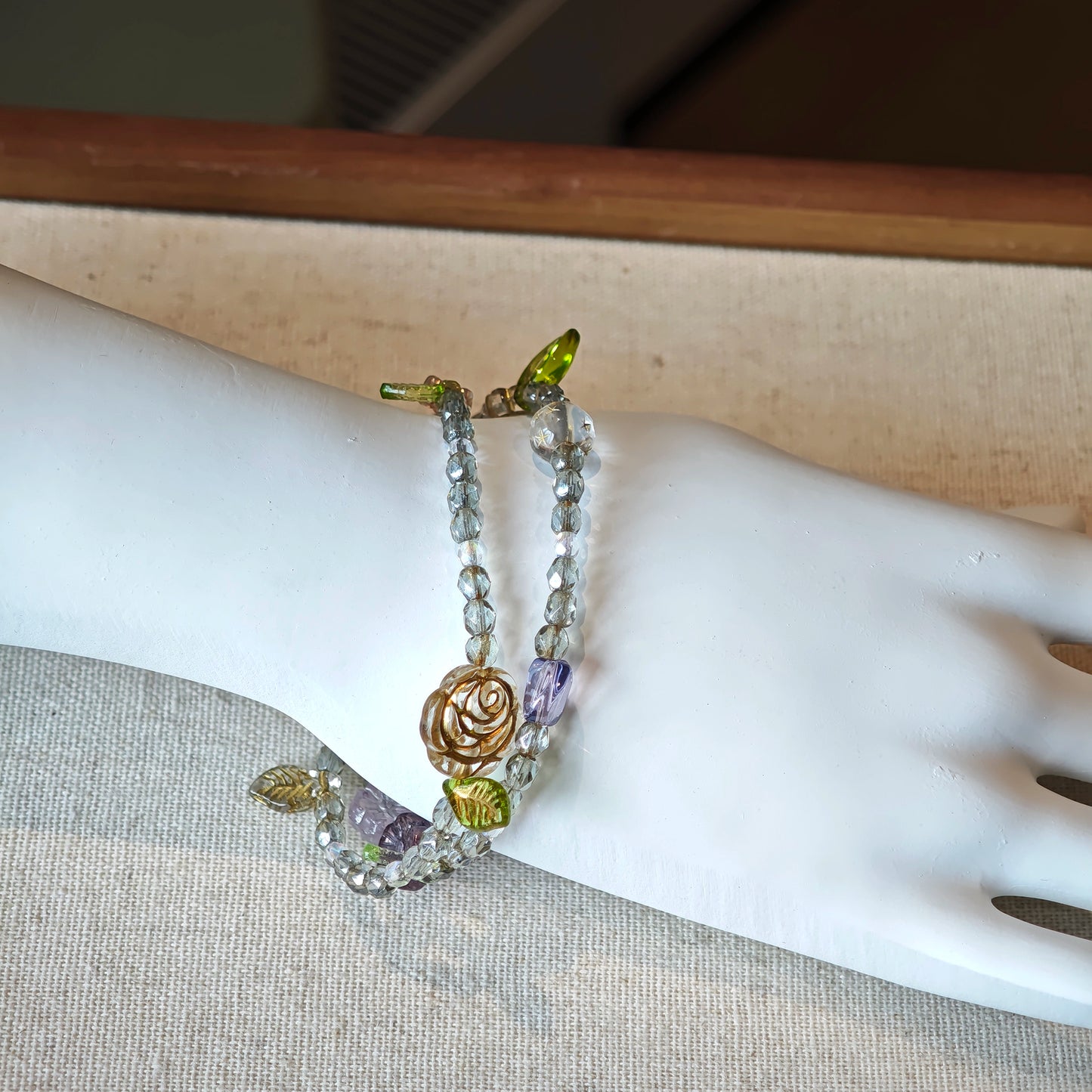 This is a grey czech beads bracelet, decorated with green leaves , bronze and purple flowers, and irregularly shape amber color spacer beads.