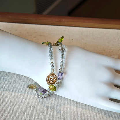 This is a grey czech beads bracelet, decorated with green leaves , bronze and purple flowers, and irregularly shape amber color spacer beads.