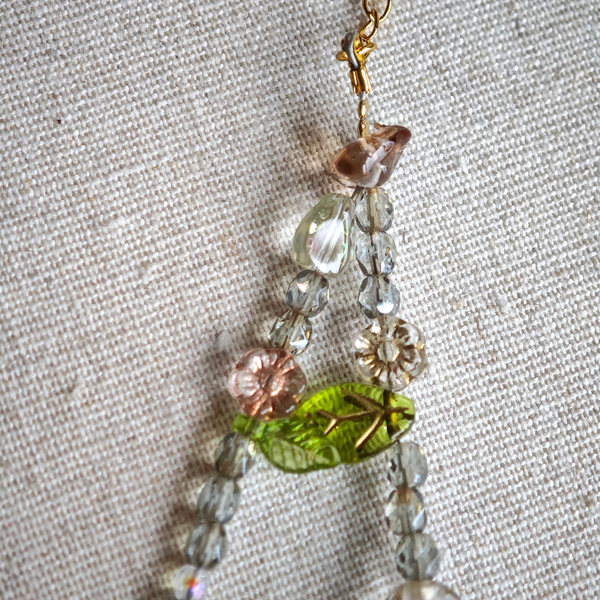 This is a grey czech beads bracelet, decorated with green leaves , bronze and purple flowers, and irregularly shape amber color spacer beads.