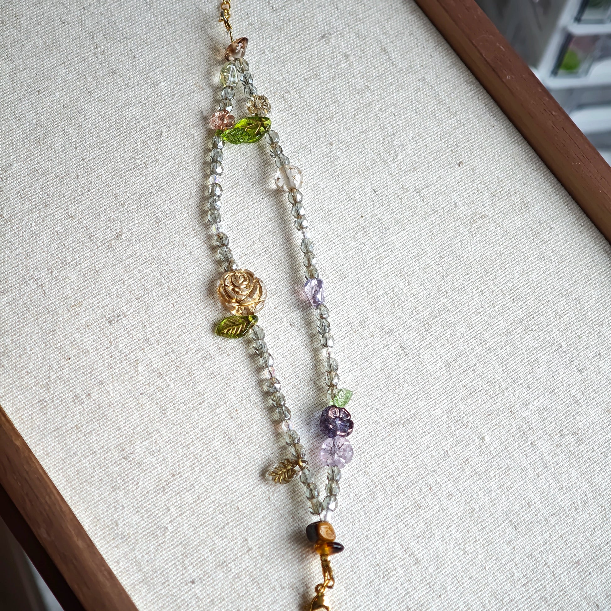 This is a grey czech beads bracelet, decorated with green leaves , bronze and purple flowers, and irregularly shape amber color spacer beads.