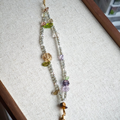 This is a grey czech beads bracelet, decorated with green leaves , bronze and purple flowers, and irregularly shape amber color spacer beads.