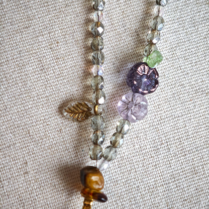 This is a grey czech beads bracelet, decorated with green leaves , bronze and purple flowers, and irregularly shape amber color spacer beads.