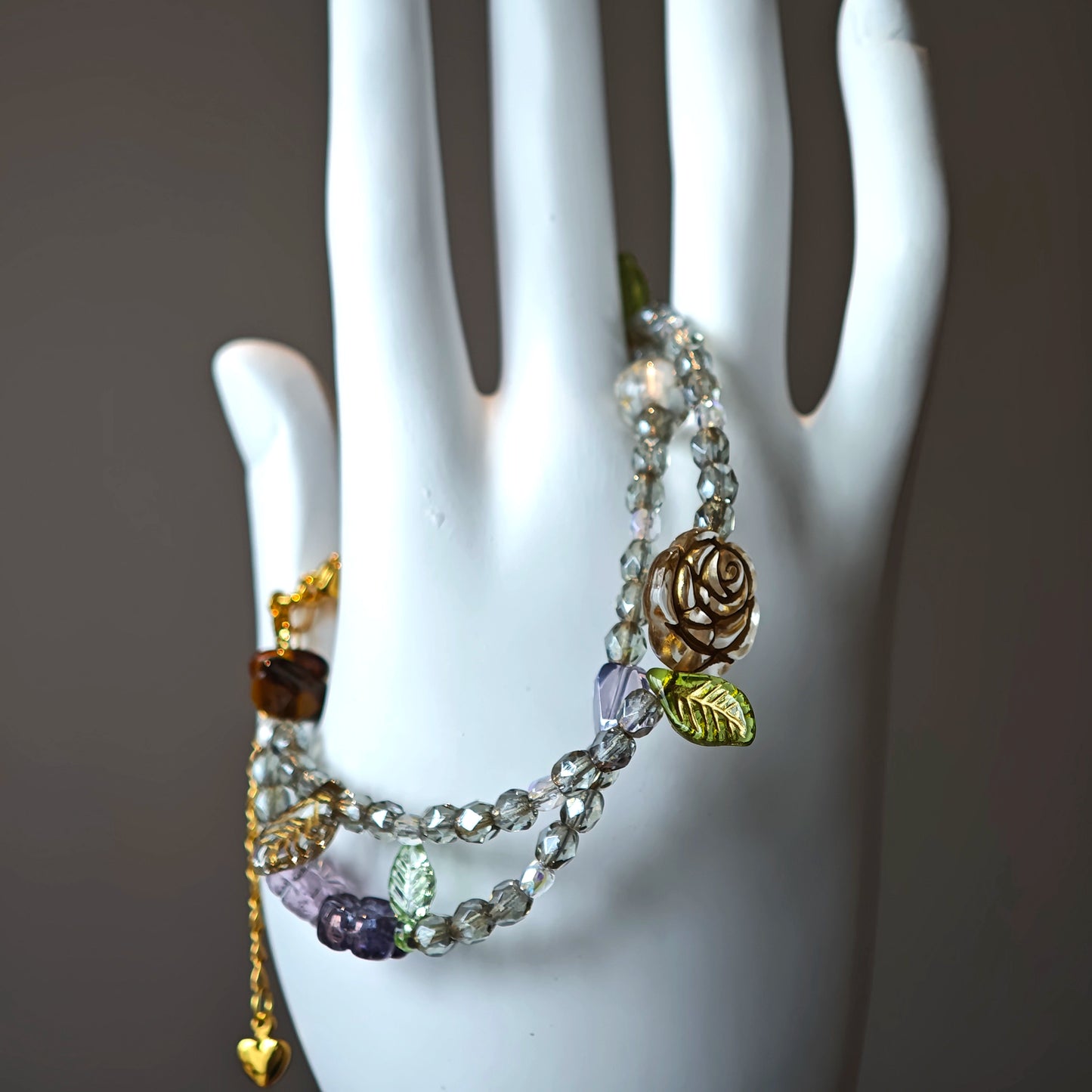 This is a grey czech beads bracelet, decorated with green leaves , bronze and purple flowers, and irregularly shape amber color spacer beads.