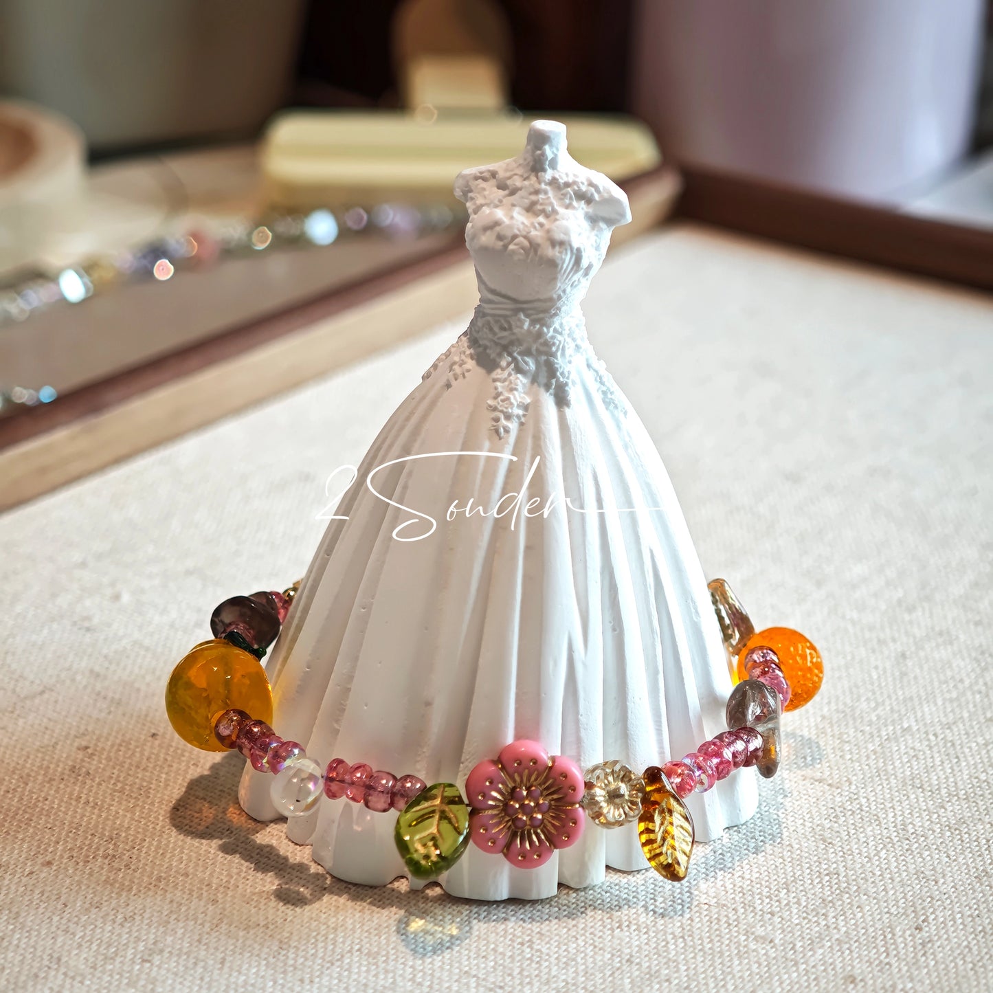This is a bracelet consist of glass beads. The main color of the bracelet is pink. It's also decorated with orange, yellow pear, grey flower, brown leaves and green leaves spacers.