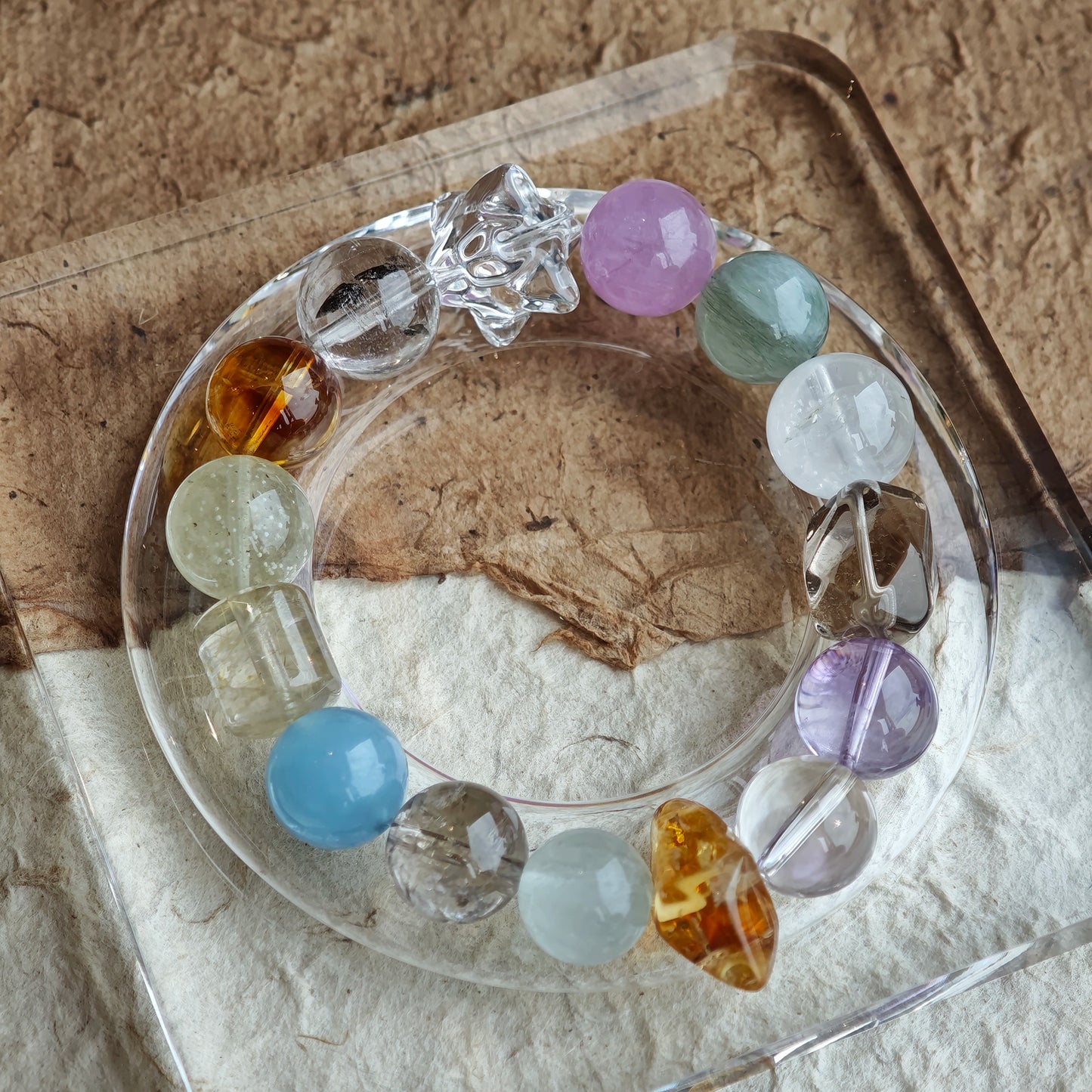 The strand feels like dawn over water: pale blues, lilacs, golds, greens, and drifting white.